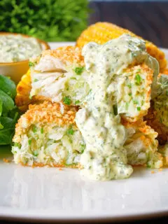 Homemade baked crab cakes cut open to show texture served with tartar sauce.