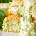 Close-up homemade crab cakes cut open to show texture served with tartar sauce.