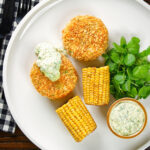 Overhead baked crab cakes with fennel and chives served with homemade tartar sauce.