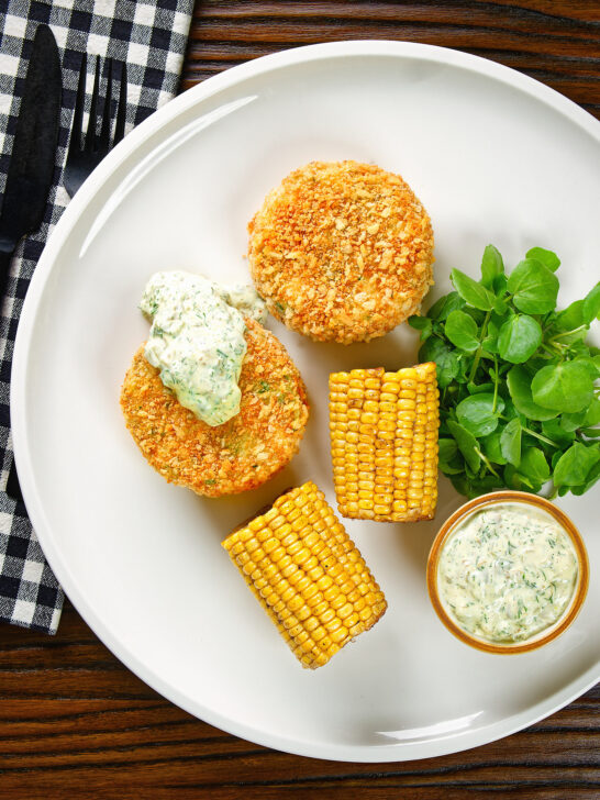 Overhead baked crab cakes with fennel and chives served with homemade tartar sauce.