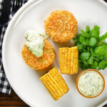 Overhead baked crab cakes with fennel and chives served with homemade tartar sauce.