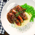 Overhead devilled sausages in a spicy onion gravy with mashed potato and peas.