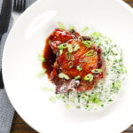 Overhead Filipino-inspired adobo pork chops served with rice and spring onions.