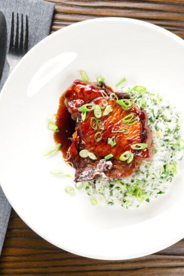 Overhead Filipino-inspired adobo pork chops served with rice and spring onions.