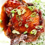 Cloe-up overhead Filipino-inspired adobo pork chops served with rice and spring onions.