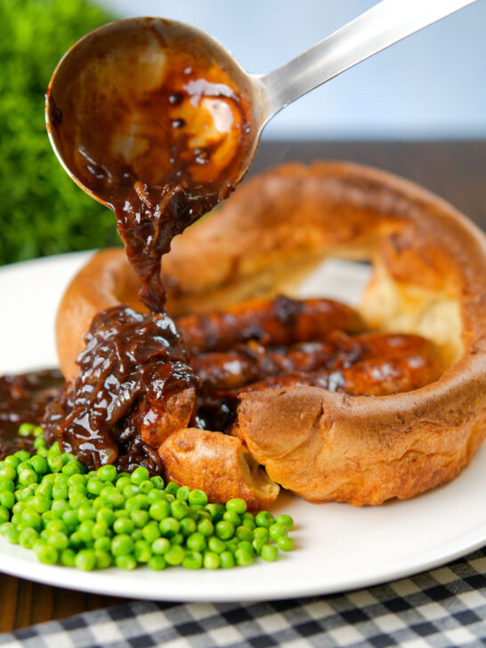 Onion gravy being poured over a single serving toad in the hole.