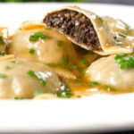 Mushroom filled ravioli in a marsala wine, butter and chive sauce, cut open to show the filling.