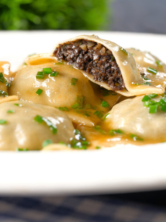 Mushroom filled ravioli in a marsala wine, butter and chive sauce, cut open to show the filling.