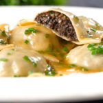 Mushroom filled ravioli in a marsala wine, butter and chive sauce, cut open to show the filling.