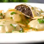 Mushroom filled ravioli in a marsala wine, butter and chive sauce, cut open to show the filling.