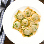Overhead homemade mushroom filled ravioli in a marsala wine, butter and chive sauce.