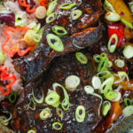 Close-up Overhead Jamaican brown stew chicken with spring onions, rice and peas.