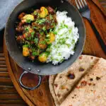 Overhead pork belly curry with tamarind, black pepper and whole garlic cloves served with rice and chapatis.