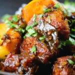 Close-up pork belly curry with tamarind, black pepper and whole garlic cloves.