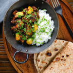 Overhead pork belly curry with tamarind, black pepper and whole garlic cloves served with rice and chapatis.