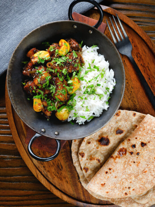 Overhead pork belly curry with tamarind, black pepper and whole garlic cloves served with rice and chapatis.