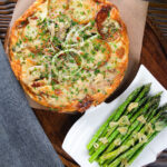 Overhead potato and onion frittata with smoked mackerel and capers served with garlic asparagus.