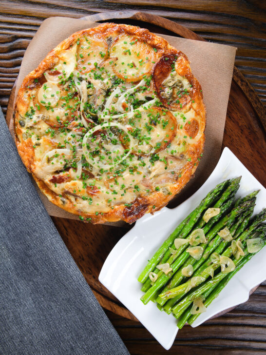 Overhead potato and onion frittata with smoked mackerel and capers served with garlic asparagus.