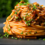 Spaghetti alla puttanesca garnished with freshly chopped parsley.