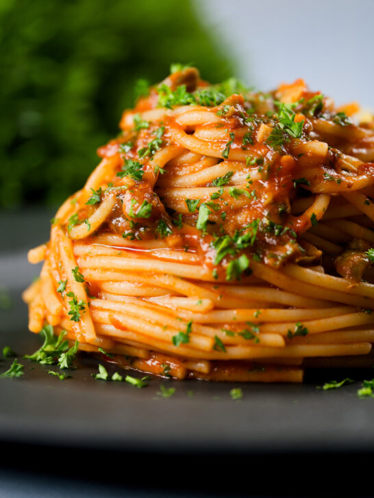 Spaghetti alla puttanesca garnished with freshly chopped parsley.