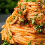 Close-up spaghetti alla puttanesca garnished with freshly chopped parsley.