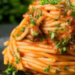 Close-up spaghetti alla puttanesca garnished with freshly chopped parsley.