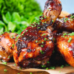 Close-up baked sticky chicken drumsticks with a cherry and balsamic vinegar glaze.