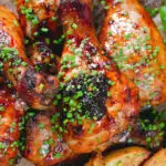 Close-up overhead baked sticky chicken drumsticks with a cherry balsamic glaze served with wedges.