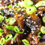 Close-up teriyaki mushrooms stir fry served with egg fried rice and spring onions.