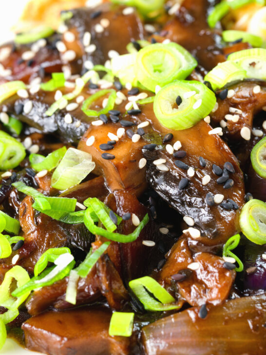 Close-up teriyaki mushrooms stir fry served with egg fried rice and spring onions.