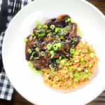 Overhead teriyaki mushrooms stir fry served with egg fried rice and spring onions.