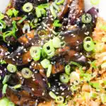 Close-up overhead teriyaki mushrooms stir fry served with egg fried rice and spring onions.