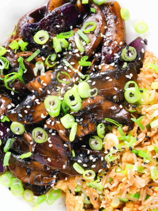 Close-up overhead teriyaki mushrooms stir fry served with egg fried rice and spring onions.