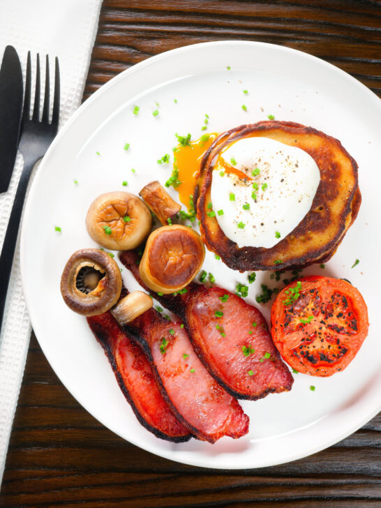 Overhead Irish boxty pancakes with poached egg, bacon, tomato and mushrooms.