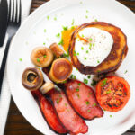 Overhead Irish boxty pancakes with poached egg, bacon, tomato and mushrooms.