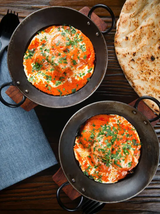 Overhead rich and creamy Indian butter chicken curry or murgh makhani served with naan bread.