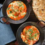 Overhead rich and creamy Indian butter chicken curry or murgh makhani served with naan bread.