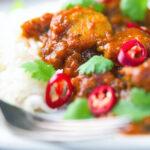 Close-up hot, sweet and sour Indian chicken pathia curry with rice and coriander.
