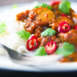 Close-up hot, sweet and sour Indian chicken pathia curry with rice and coriander.