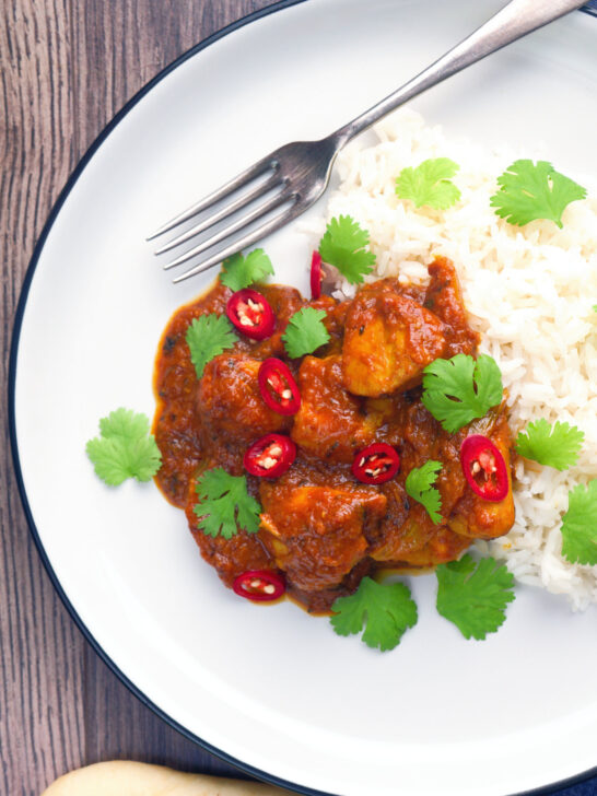 Overhead hot, sweet and sour Indian chicken pathia curry with rice and coriander.