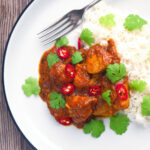 Overhead hot, sweet and sour Indian chicken pathia curry with rice and coriander.