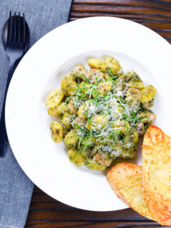 Overhead garlic chicken and basil pesto gnocchi served with cheesy garlic bread.