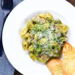 Overhead garlic chicken and basil pesto gnocchi served with cheesy garlic bread.