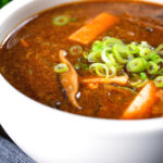 Close-up vegetarian Chinese hot and sour soup garnished with spring onions.