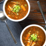 Overhead vegetarian Chinese hot and sour soup garnished with spring onions.
