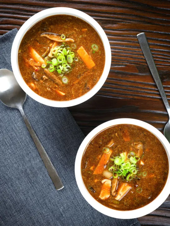 Overhead vegetarian Chinese hot and sour soup garnished with spring onions.