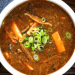 Close-up overhead vegetarian Chinese hot and sour soup garnished with spring onions.