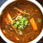 Close-up overhead vegetarian Chinese hot and sour soup garnished with spring onions.