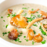 Close-up creamy wild mushroom soup garnished with fried mushrooms.