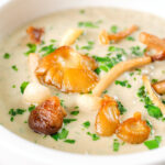 Close-up creamy wild mushroom soup garnished with fried mushrooms.